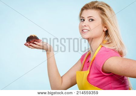Diet sweets food concept. Woman holding delicious chocolate cupcake with peanut frosting about to take bite