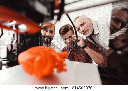 Three men are working to prepare printed model on the 3d model of the heart. They are satisfied with the result. They peer through the working field 3e of the printer.