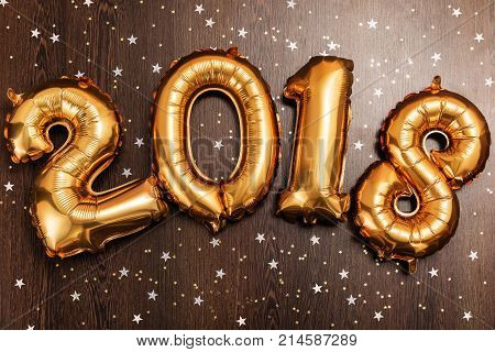 Bright gold balloons figures 2018, New Year Balloons with glitter stars on dark wood table background. Christmas and new year celebration