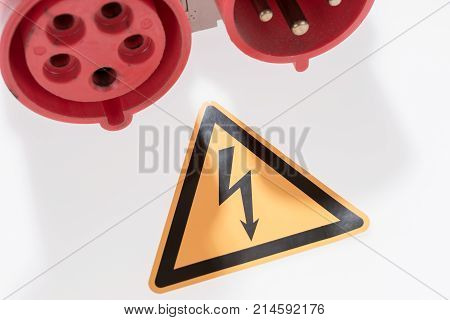 Red and white three-phase plug and socket with warning sign isolated