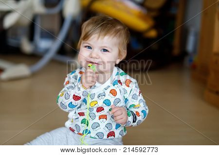 Adorable cute beautiful little baby girl playing with educational toys at home or nursery. Happy healthy child having fun with colorful different toys. Kid learning different skills