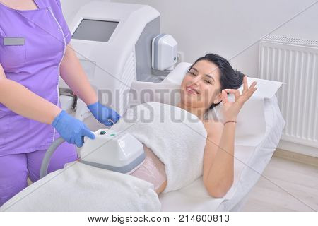 Pretty young woman getting cryolipolyse fat treatment in professional cosmetic cabinet