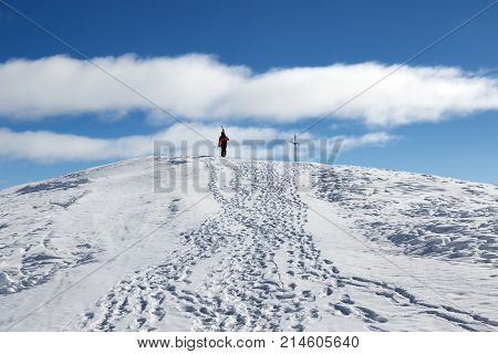 Skier with skis on his shoulder go up to top of mountain in nice sun day. Caucasus Mountains in winter Georgia region Gudauri Mount Kudebi.