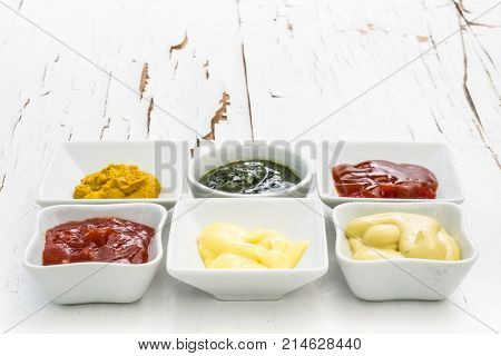 Classic set of sauces in square white sausers on surface with cracked paint