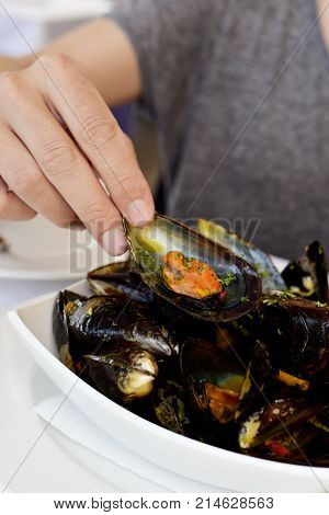 closeup of a young man eatign some mejillones a la marinera, spanish mussels in marinara sauce