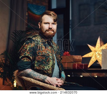 Redhead bearded male in a room with Christmas decoration.