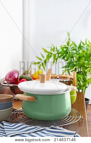 Stewpan, bowls and vegetables on wooden table in kitchen