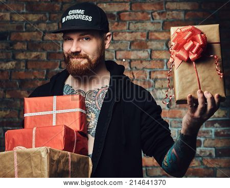 The positive Redbeard male holds Christmas gifts over the wall of a brick.