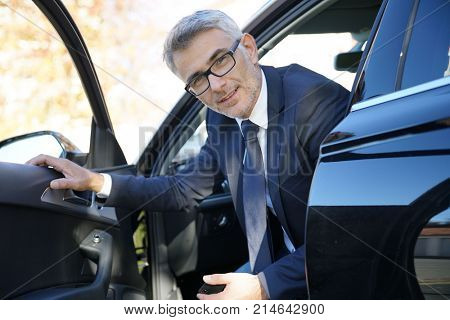 Smiling businessman getting off the car