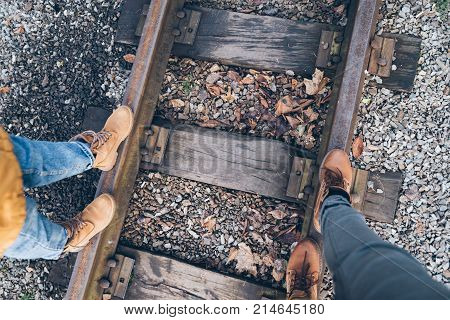 first person view down on the boots couple walk by railroad in autumn day