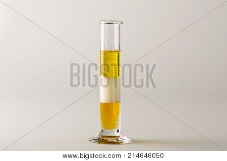 Physics. Density column. Test tube containing separed layers of vegetable oil milk and honey.