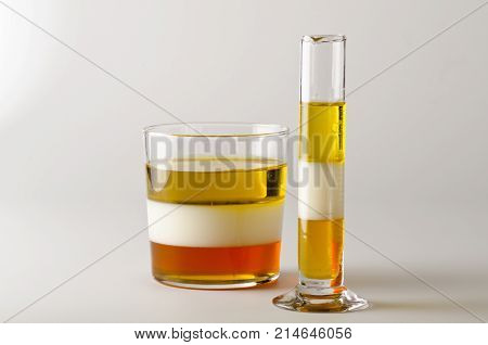 Physics. Density column. Laboratory glassware containing separed layers of vegetable oil milk and honey.