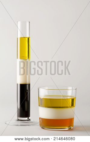Physics. Density column. Test tube containing separed layers of vegetable oil milk honey and maple syrup.