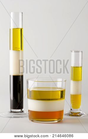 Physics. Density column. Laboratory glassware containing separed layers of vegetable oil milk and maple syrup.
