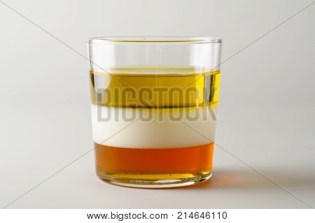 Physics. Density column. Laboratory glassware containing separed layers of vegetable oil milk and honey.