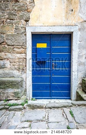 Blue Entrance Door With A Mailbox To A House On Stone Street In