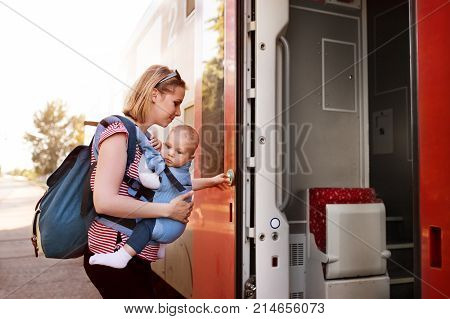 Young mother travelling with baby boy by train. Railway journey of a beautiful woman and her son.