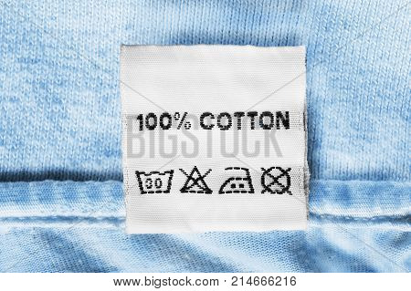 Fabric composition and washing instructions clothes label on blue cotton closeup