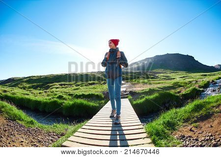 portrait of woman traveler with small orange backpack on a walk in the Valley of the river of Hveragerdi Iceland. Hiking Tour of Reykjadalur Hot Springs