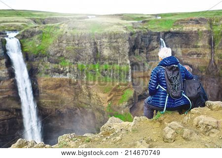 famous Haifoss waterfall in southern Iceland. treking in Iceland. elderly hikers sitting on the edge of a cliff and looking at waterfall