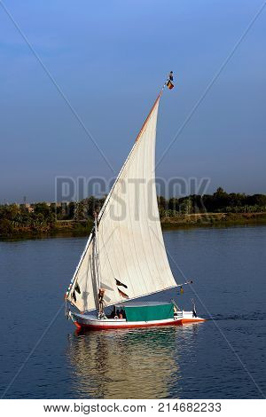 Felucca at disk with white sails, sailing along the Nile River - Egypt