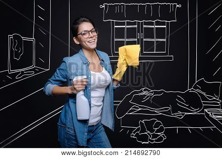Every day chores.Cheerful smiling house wife holding rag and clening her bedroom while doing spring cleaning