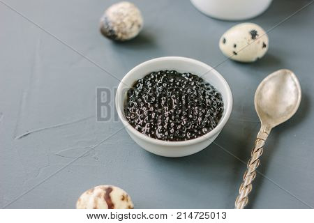 A black caviar in a white ceramic bowl.