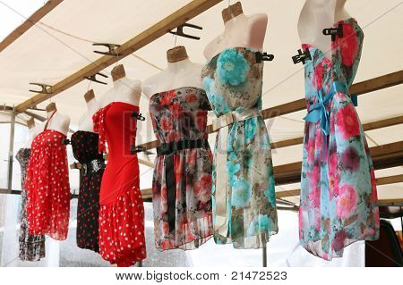 Řada clourfull summerdresses visící ze stánku v tržnici