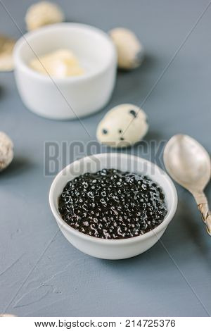 A black caviar in a white ceramic bowl.