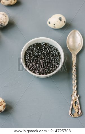 A black caviar in a white ceramic bowl.
