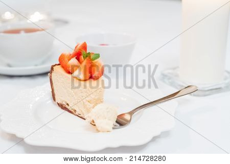 Cheesecake with strawberries and mint leaves on a white plate close up