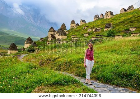 Beautiful woman is standing in front of ancient tombs of Dargavs in Ossetia, Russia