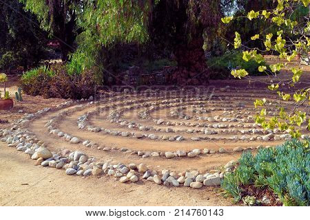 Maze of rocks creating a Labyrinth surrounded by trees and plants taken in a Zen Meditation Garden