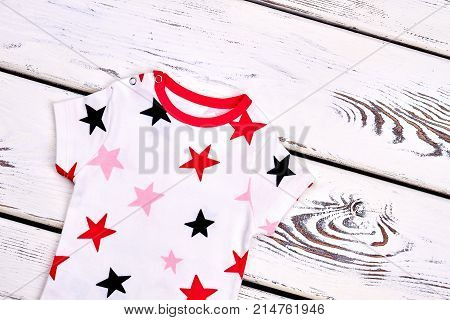 Newborn child soft printed clothes. Infant kids stars print cotton garment on old wooden background. Beautiful kids apparel on sale.