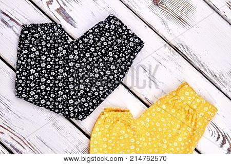 Baby-girl harem floral trousers. Toddler girl summer harems on old wooden background. Infant girl new patterned pants.