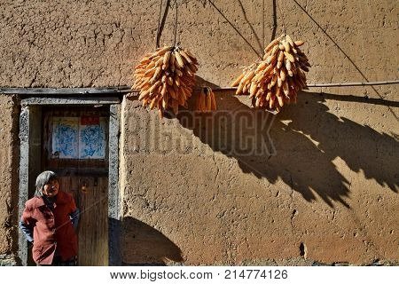 ANHUI PROVINCE, CHINA - CIRCA OCTOBER 2017: An old women in front of her house in the Yangchan tulou, the chinese rural earthen dwelling in Anhui province in China.