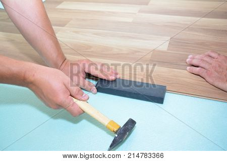 Contractors installing wooden laminate flooring with insulation and soundproofing sheets. Man laying laminate flooring. Man laying laminate flooring.