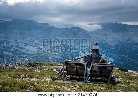 Obertraun, Austria - August 5, 2017:  Unidentified people relaxing on sunbed looking at glacier in the mountains. Hoher Dachstein, Alps, Austria