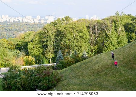 small children play on a hill in the background of the city