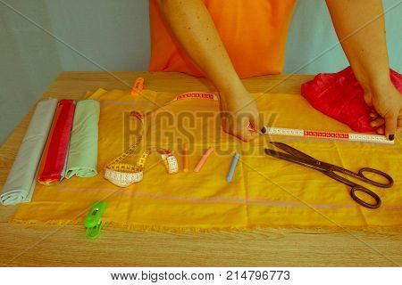 Tailor cutting fabric using large scissors or shears as he follows the chalk markings of the pattern close up of his hands. Woman's Hand Sewing Quilt