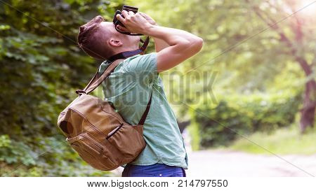 A young man takes photos of nature in the woods
