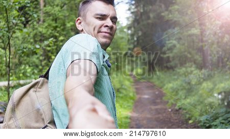 The young man pulls the girl's hand on the forest path