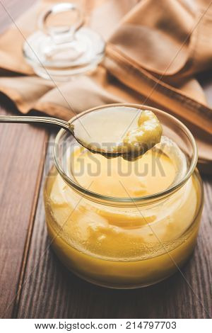 Desi Ghee or clarified butter in glass or Copper container or ceramic jar with spoon, selective focus
