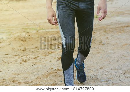 The young man is wearing sweatpants in the desert
