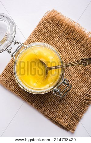 Desi Ghee or clarified butter in glass or Copper container or ceramic jar with spoon, selective focus