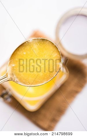 Desi Ghee or clarified butter in glass or Copper container or ceramic jar with spoon, selective focus