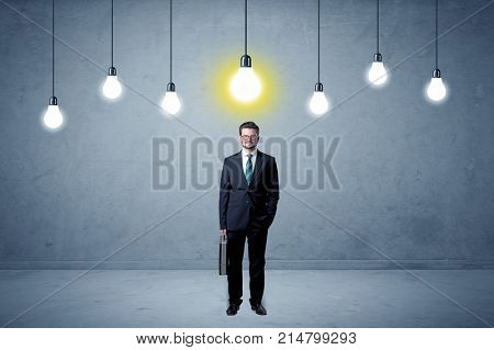 Handsome businessman in an empty space with bulbs above and uninspired face