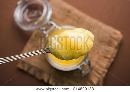 Desi Ghee or clarified butter in glass or Copper container or ceramic jar with spoon, selective focus