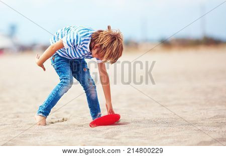 Young Boy With Flying Disk In Motion, Playing Leisure Activity Games On The Sandy Beach