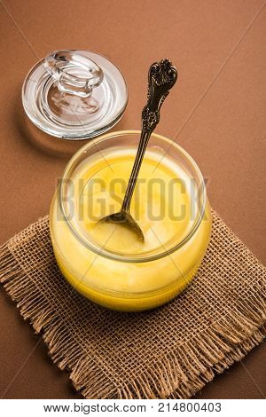 Desi Ghee or clarified butter in glass or Copper container or ceramic jar with spoon, selective focus